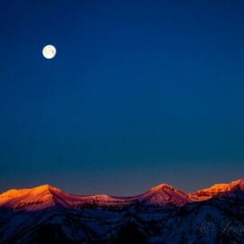 A Full Moon Hangs Over The Snow Covered Teton Mountains In Jackson Hole, Wyoming.